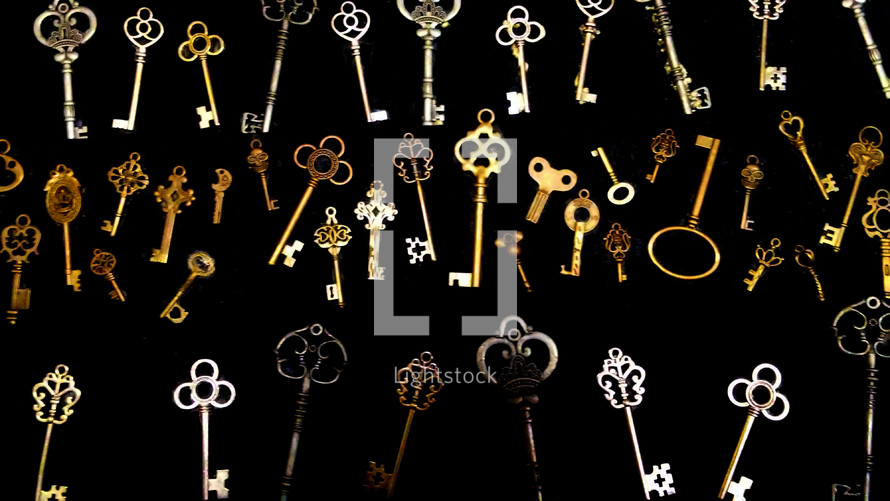 A large collection of Keys gold, brass and silver metals for unlocking doors. A collection of keys that are old and antique key collection on a black background for unlocking doors. 