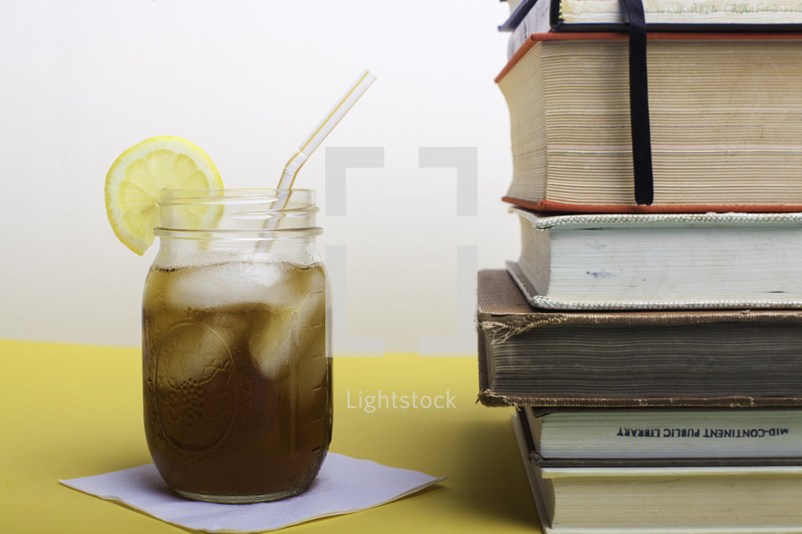 stack of books and glass of iced tea 