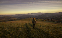 a man hiking on a mountaintop at sunset 