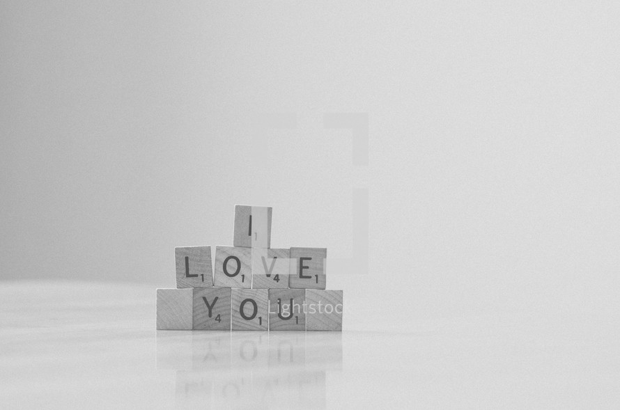 "I love you" spelled in stacked scrabble tiles in black & white.