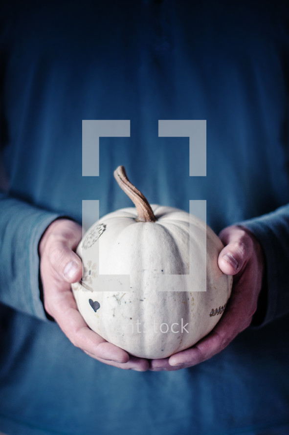 Man holding a decorated pumpkin in both hands
