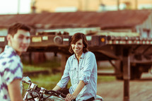 a woman sitting on a motorcycle and a man looking at the camera 