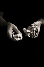 Hands holding broken bread