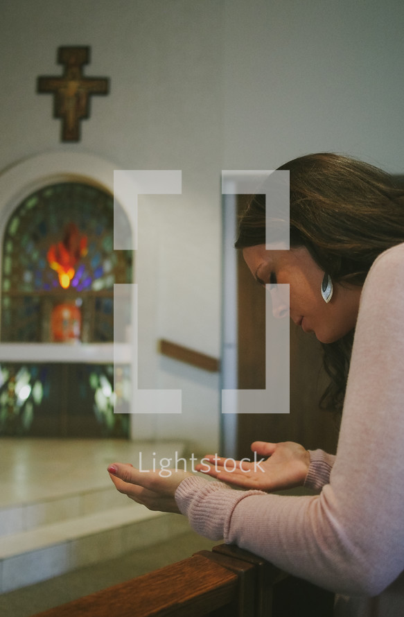 A woman kneeling in prayer in a Catholic church