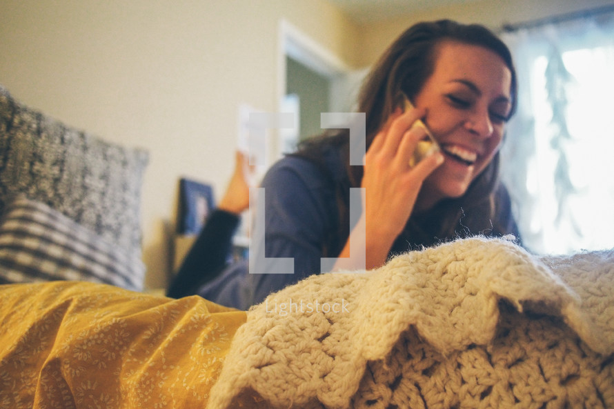 a teen girl talking on a phone in her bedroom 