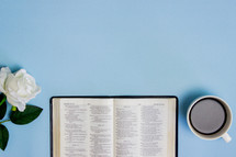 open Bible and coffee cup on a blue background 