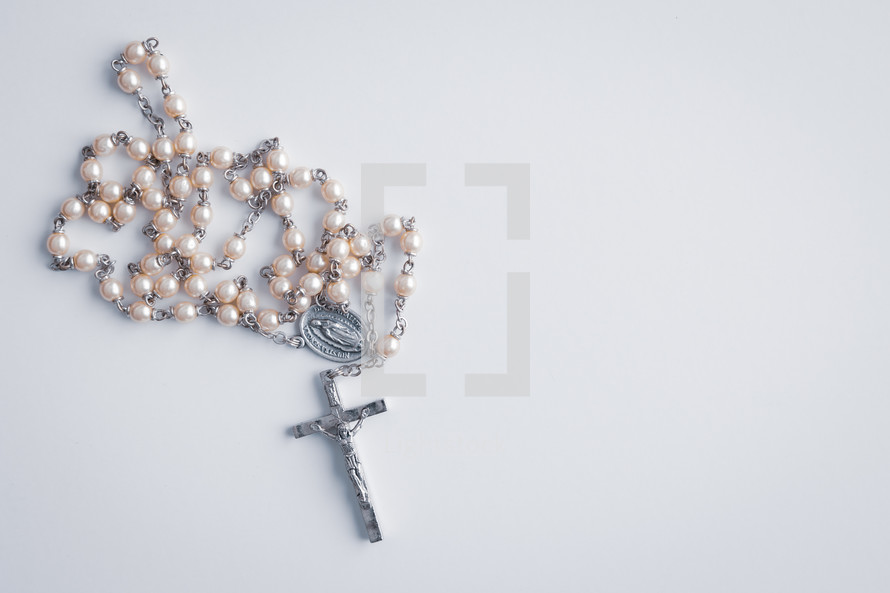 White rosary on a white background with copy space