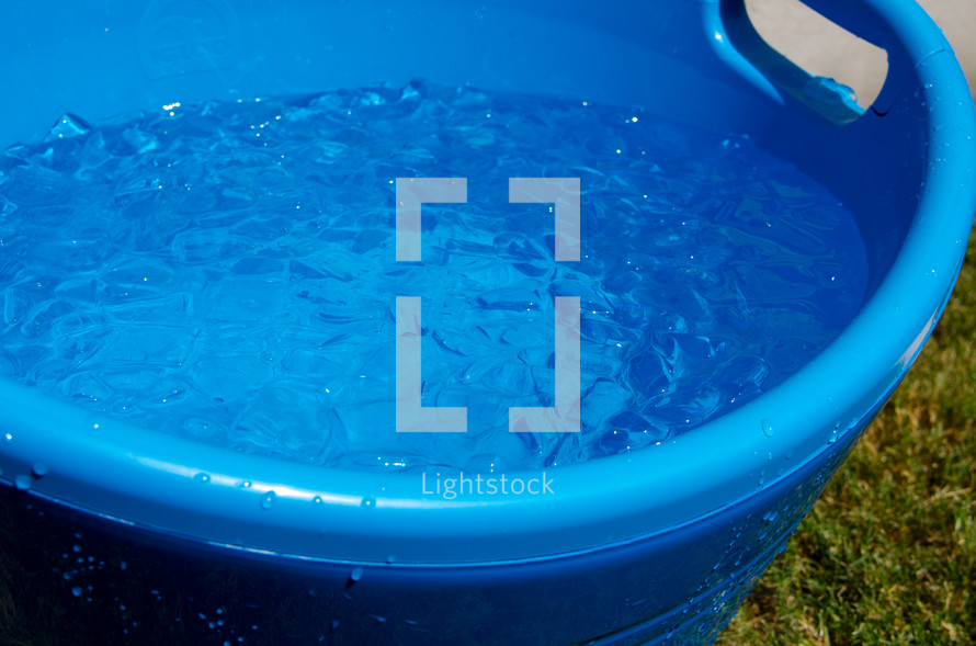 A blue plastic bucket full of ice water.