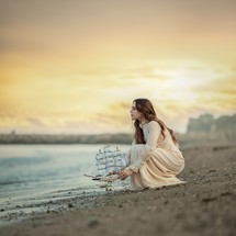 a woman on a beach with a model ship 