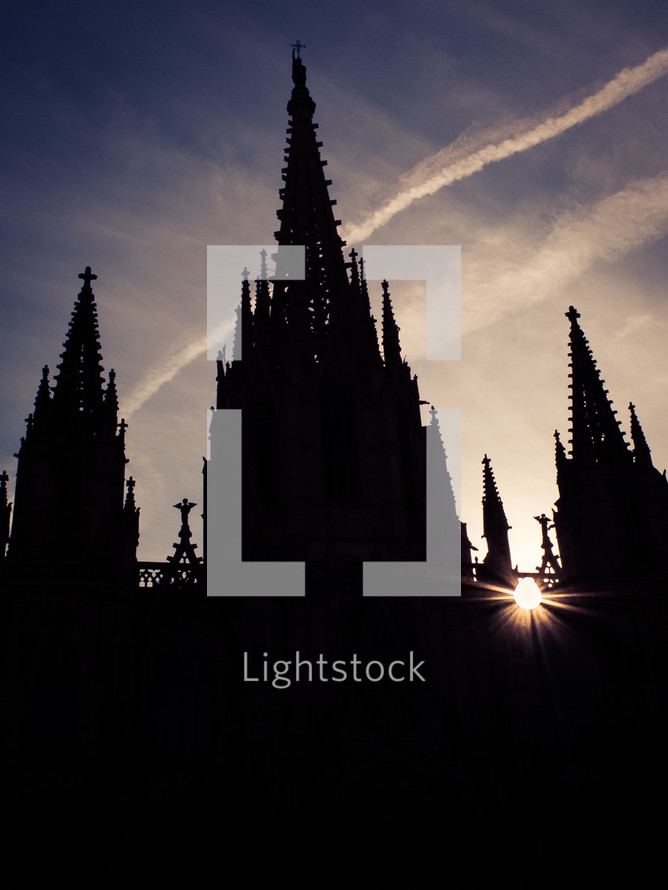 Rays of sunlight break through a silhouette of a gothic church cathedral
