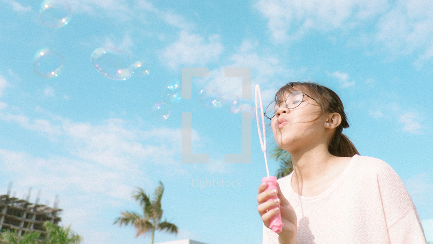 a girl blowing bubbles 