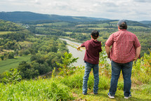 father and son looking out at a river 