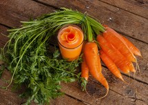 Fresh carrot juice glass with fresh organic carrots on wooden table