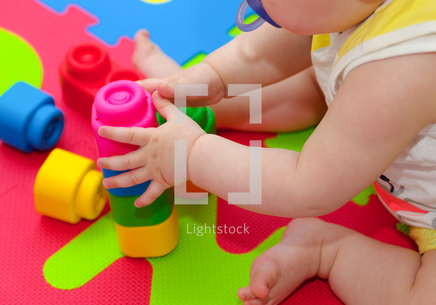 toddler plays with building blocks on the colored rubber mat