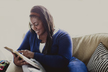 Woman sitting on the couch reading the Bible.