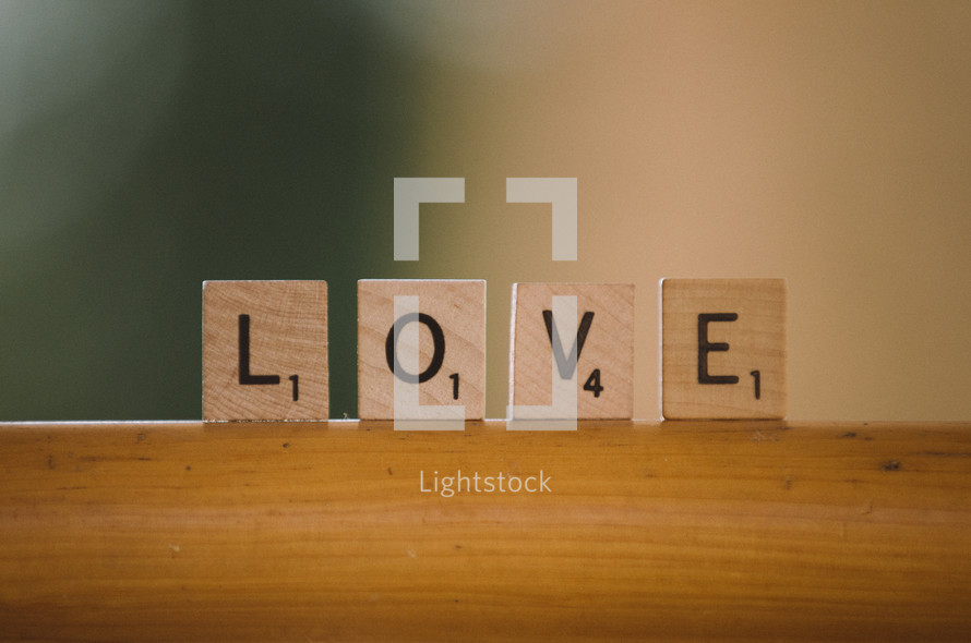Love spelled out in scrabble tiles on wooden bar.
