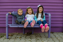 children sitting on a bench at a playground 