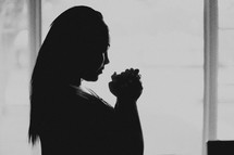 Silhouette of a praying woman.
