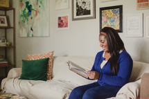 African-American woman reading a Bible on the couch 