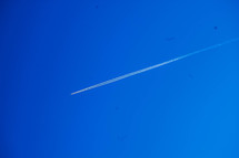 plane with contrails in a blue sky 
