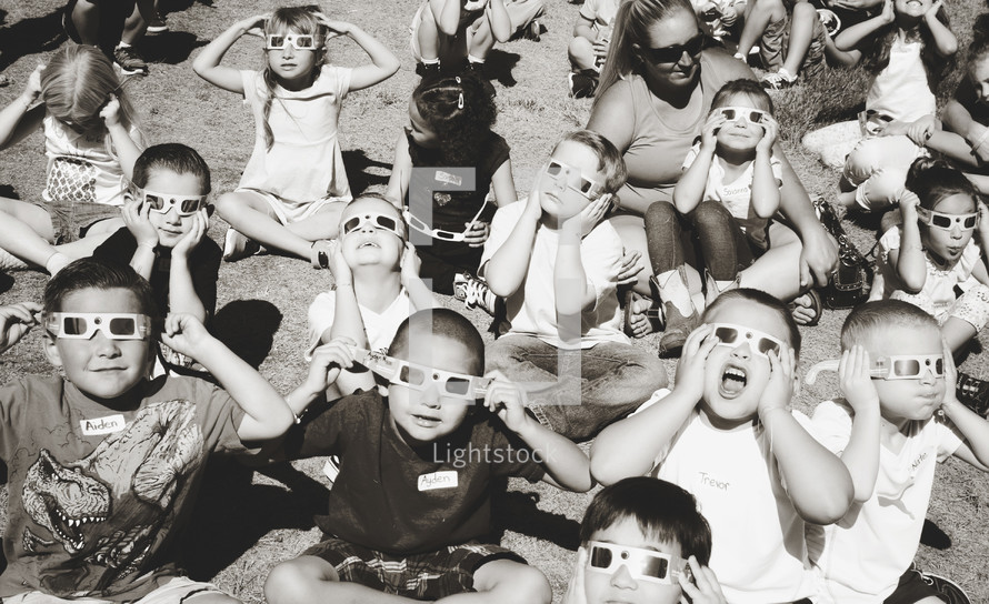 children wearing solar eclipse glasses 