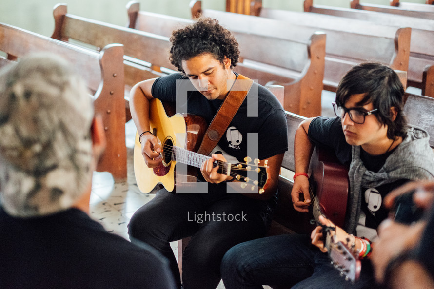 man playing a guitar in church pews in Cuba 