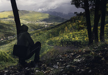 man squatting on a mountainside 