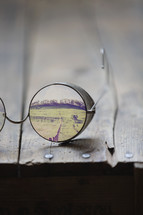 Reflection of a green landscape in an eyeglass lens.