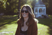 brunette woman standing outdoors wearing sunglasses 