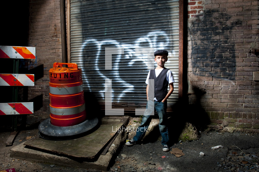 boy standing in an alley next to a construction cone