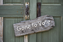 Green wooden doors with a sign reading, "Gone to Vote."