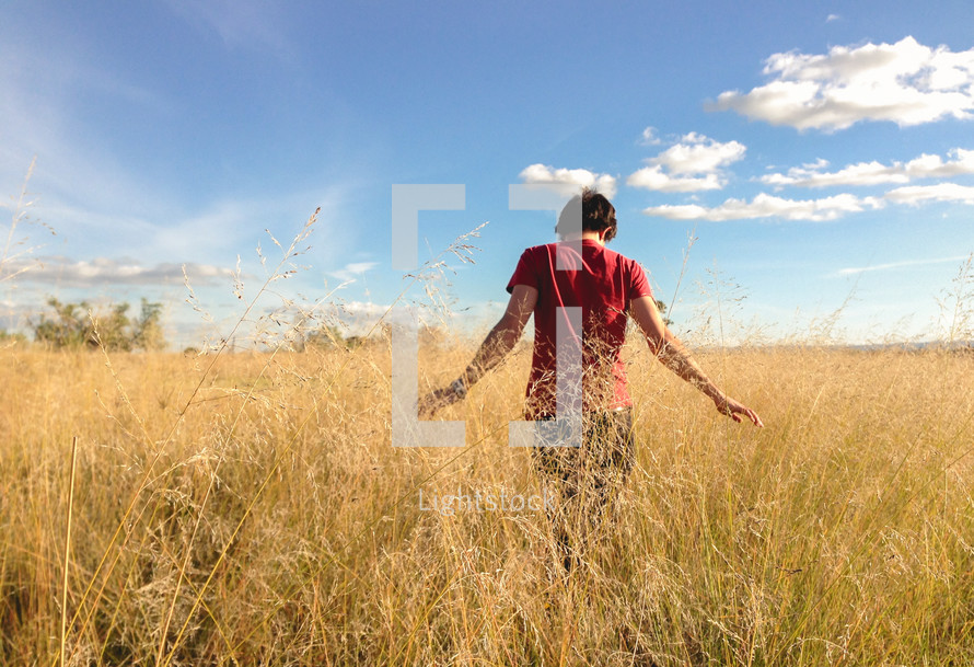 a man walking through a golden field 