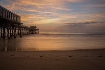 pier on a beach at sunset 