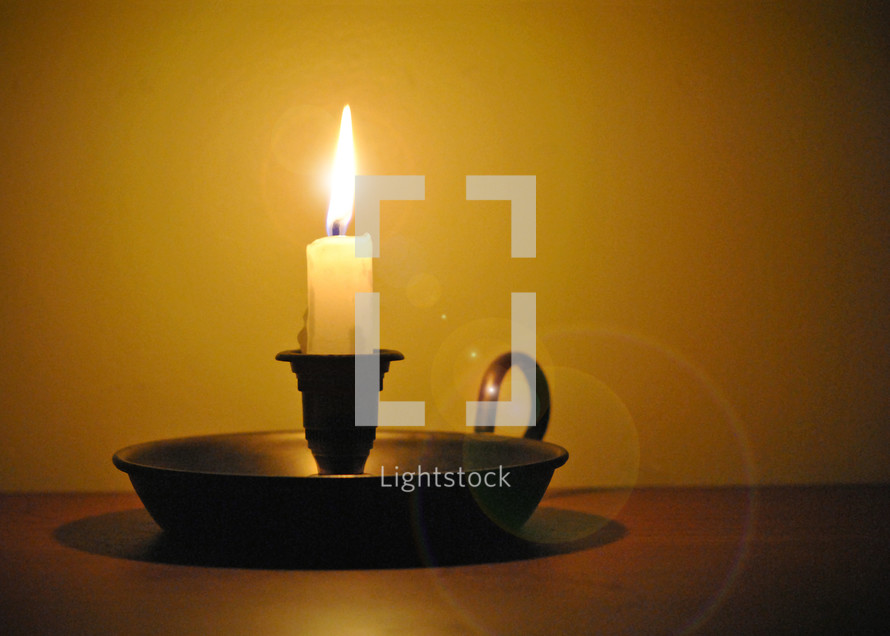 Lighted candle in candlestick.