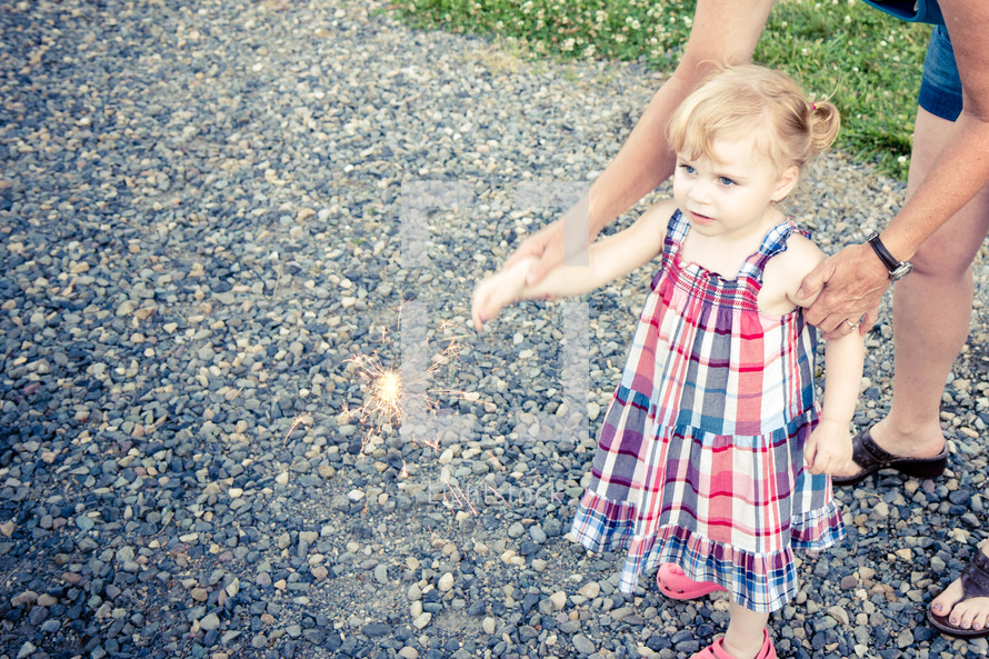 toddler and mother holding a sparkler for the 4th of July