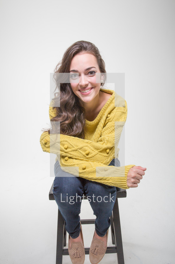 A smiling woman sitting on a stool