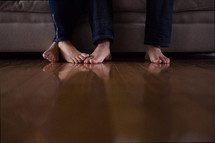 touching bare feet of a couple sitting on a couch watching tv.