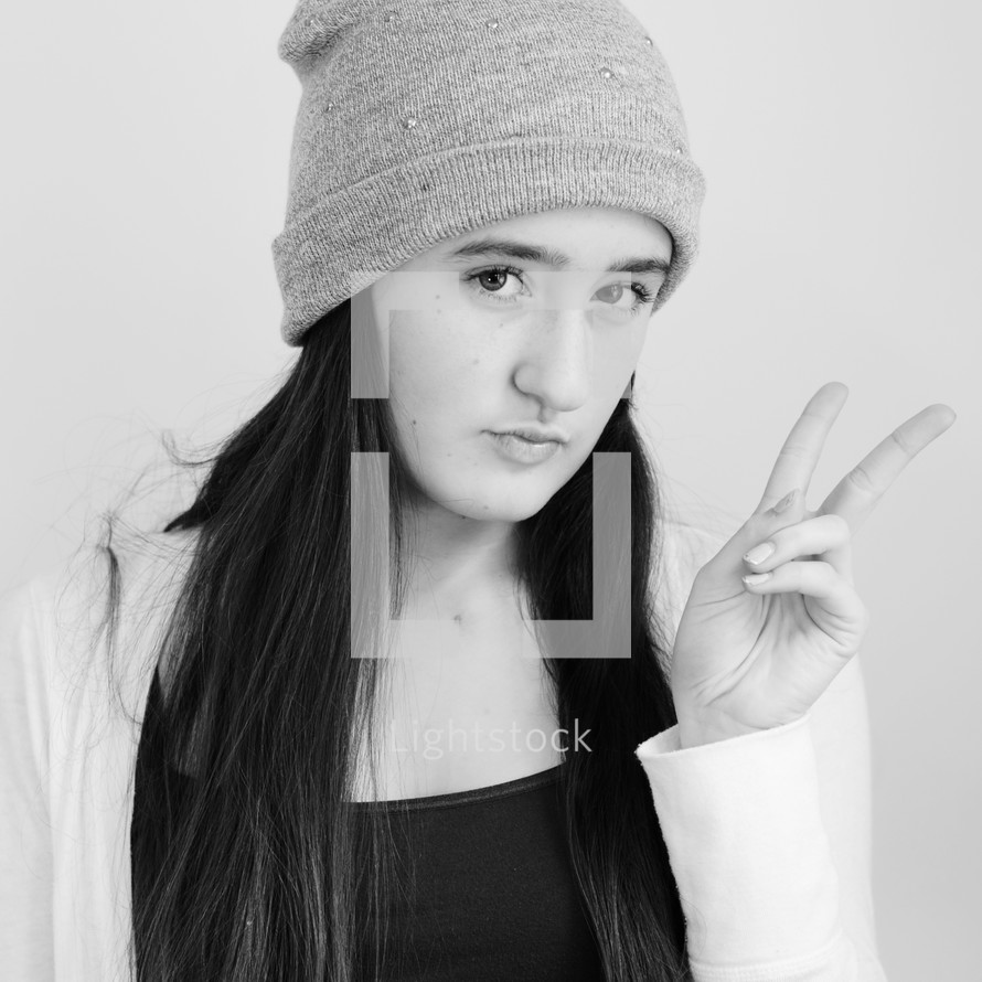 Young girl with stocking cap on giving the peace sign