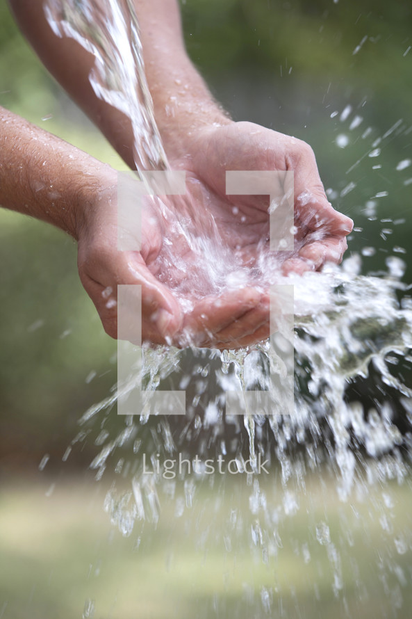 Water pouring into clasped hands.