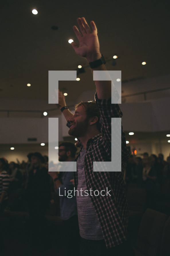 A man with hands raised in worship to God at a worship service. 