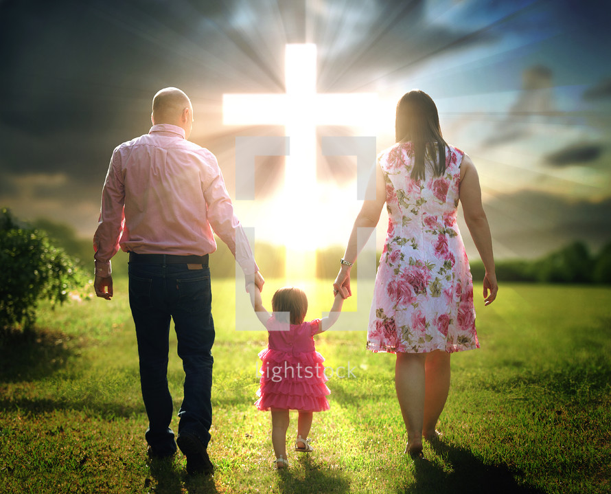 a family holding hands walking together towards a glowing cross in the sky
