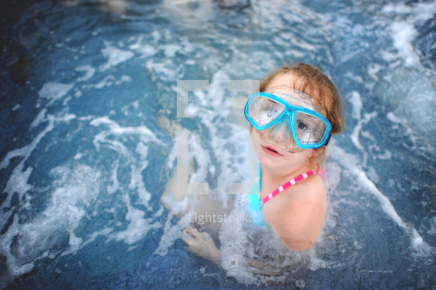 child in goggles in a pool 