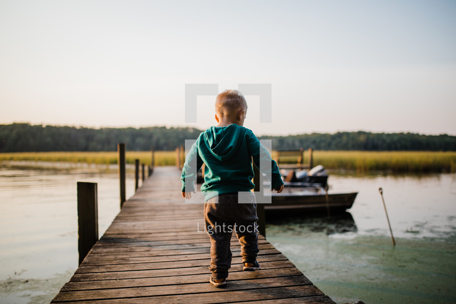 toddler boy walking on a pier 