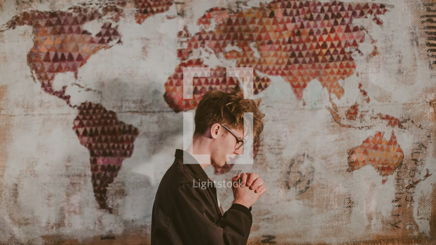 a man praying in front of a world map 