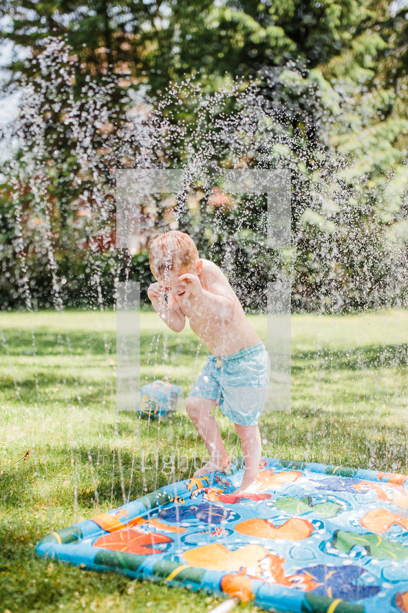 child playing in a sprinkler 