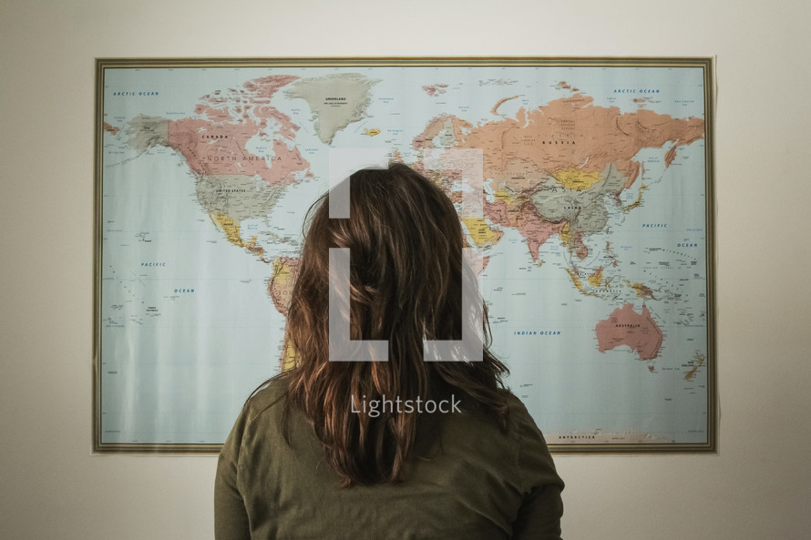 a woman standing in front of a world map 