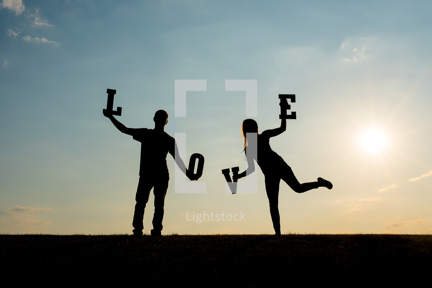 silhouettes of a couple holding up the word love 