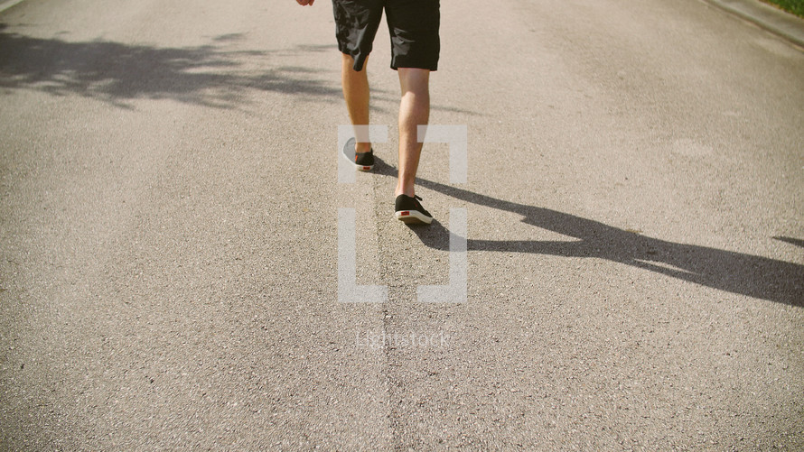 legs of a man walking on a neighborhood street 