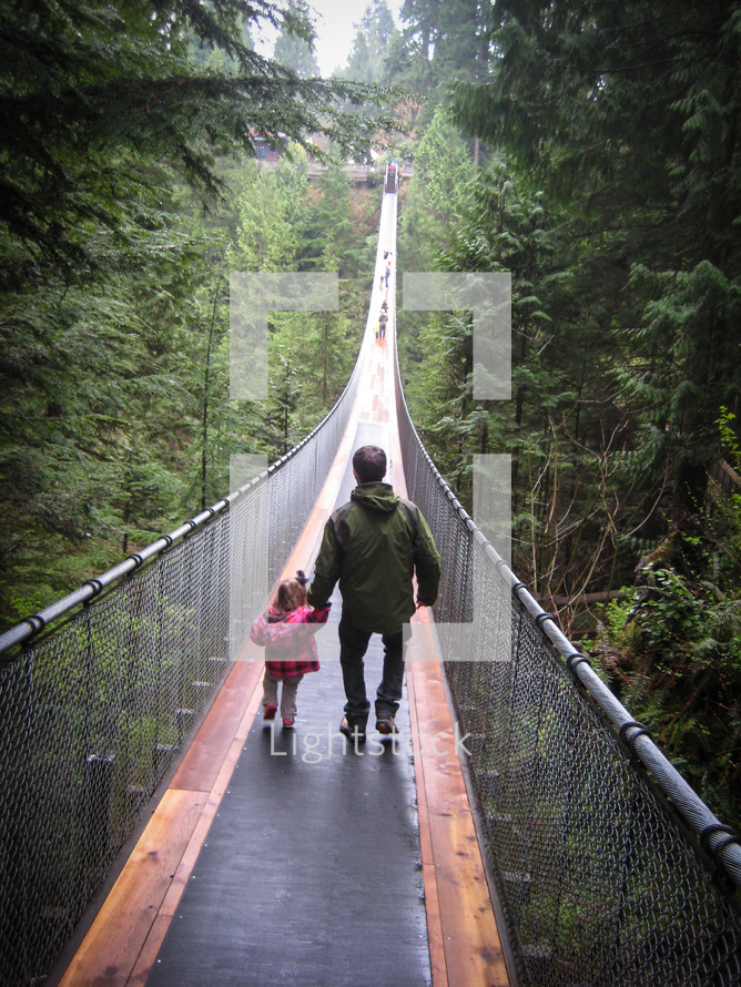 father and toddler daughter crossing a swinging bridge 