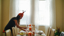 a woman in a turkey hat setting a table 